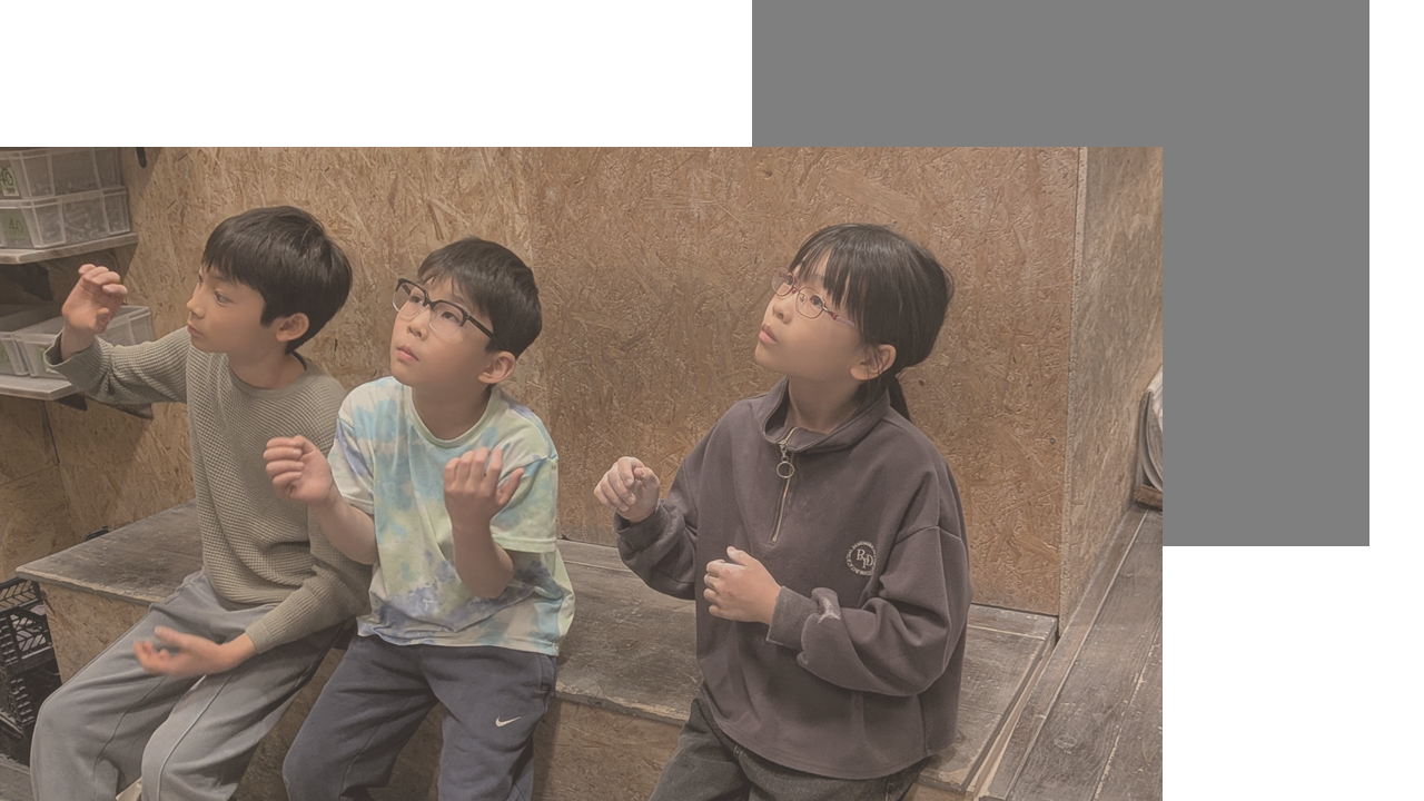 並んで座り、真剣な表情で上のウォールを見上げる3人の子供たち
