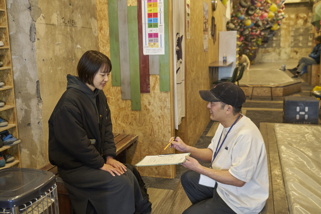 受付カウンターでスタッフが笑顔で初めてのお客様を迎える様子
